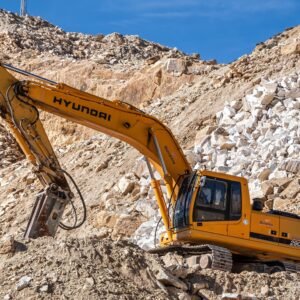 Yellow Hyundai excavator operating in a rocky quarry under a clear blue sky. Perfect for industrial themes.