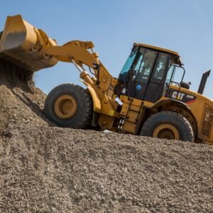 A yellow front loader moving gravel at a quarry under a blue sky.