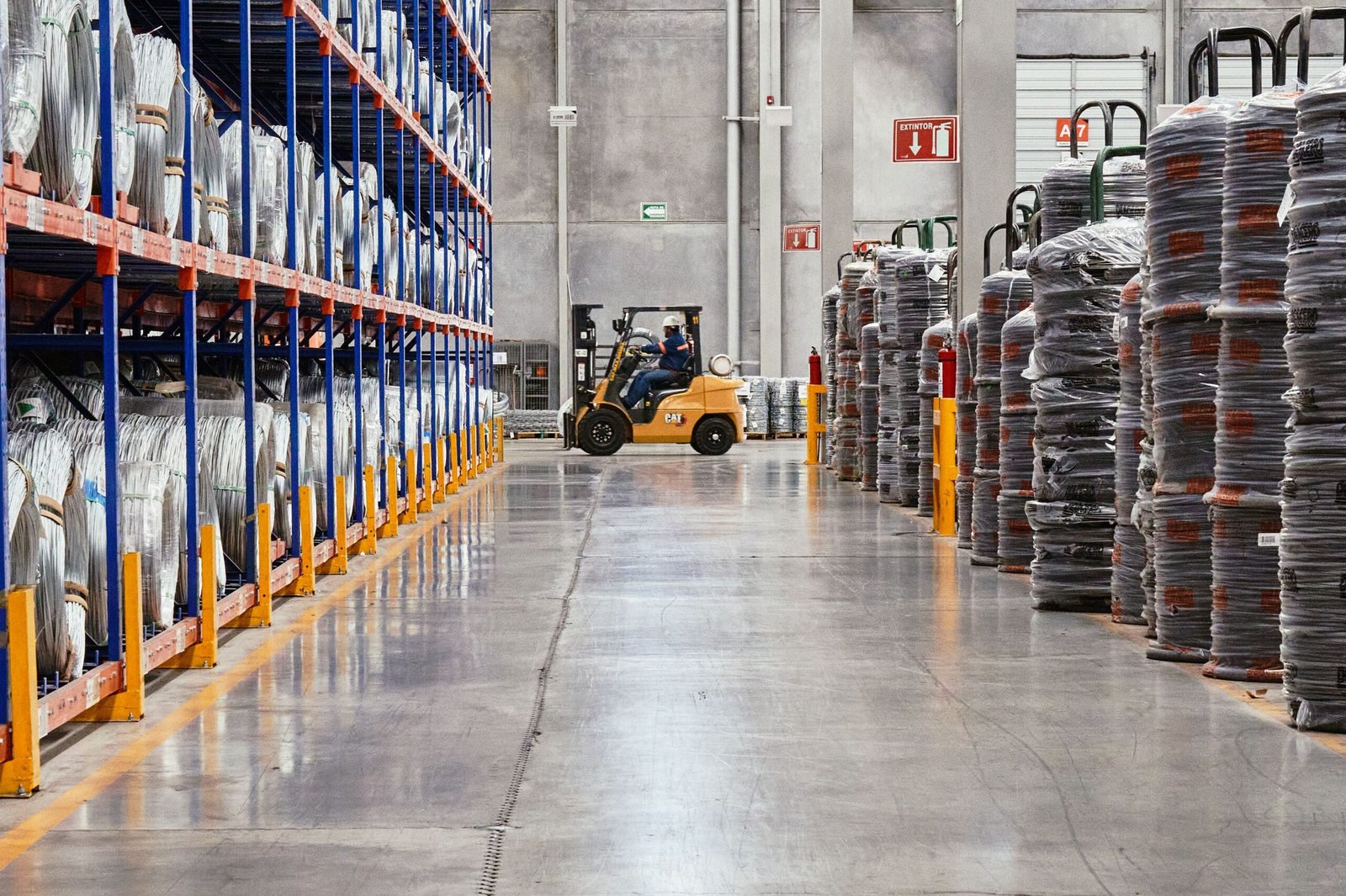 A forklift operates in an industrial warehouse with stacked goods. Efficient distribution setting.